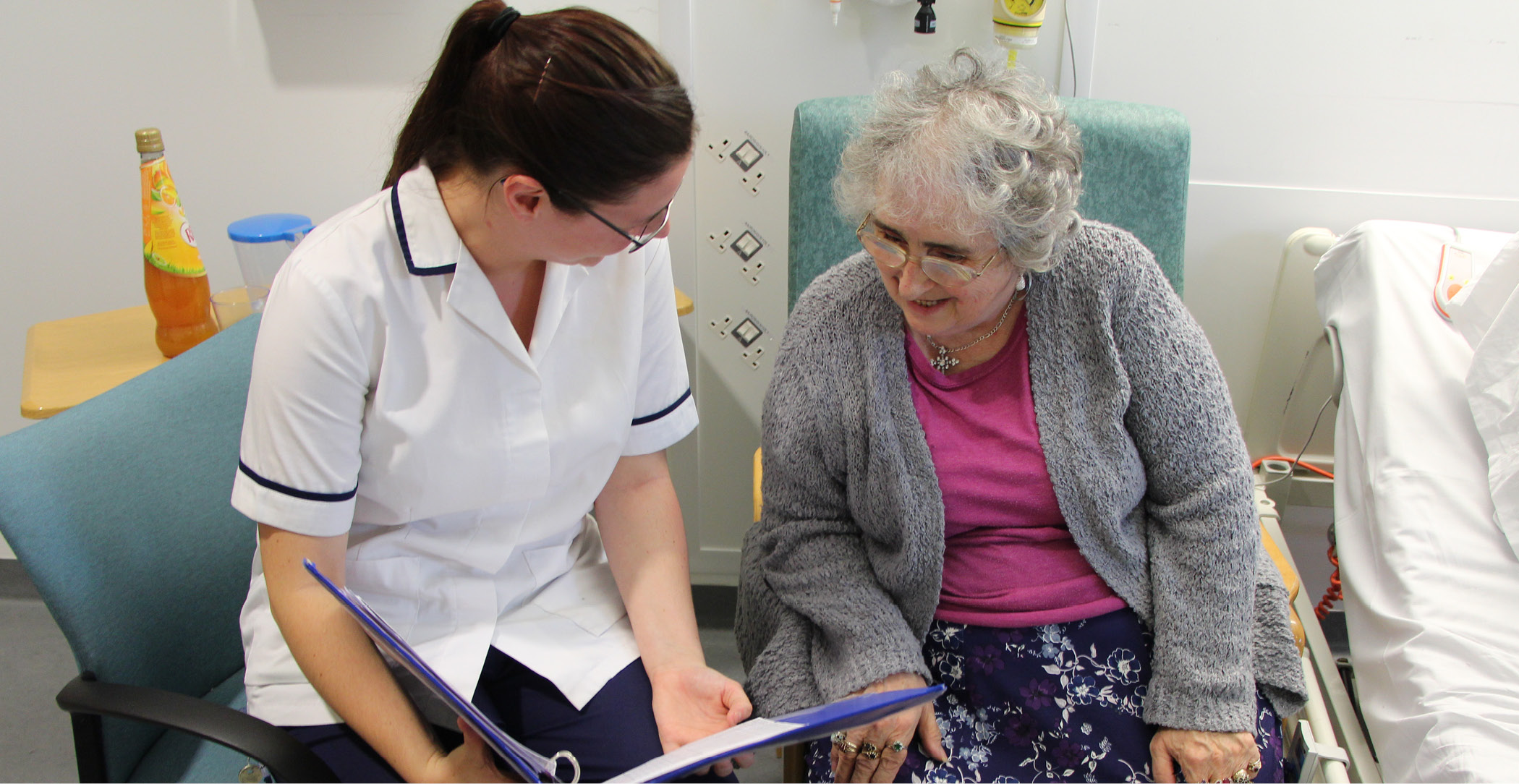 A clincian with an elderly patient, sharing information from a booklet.